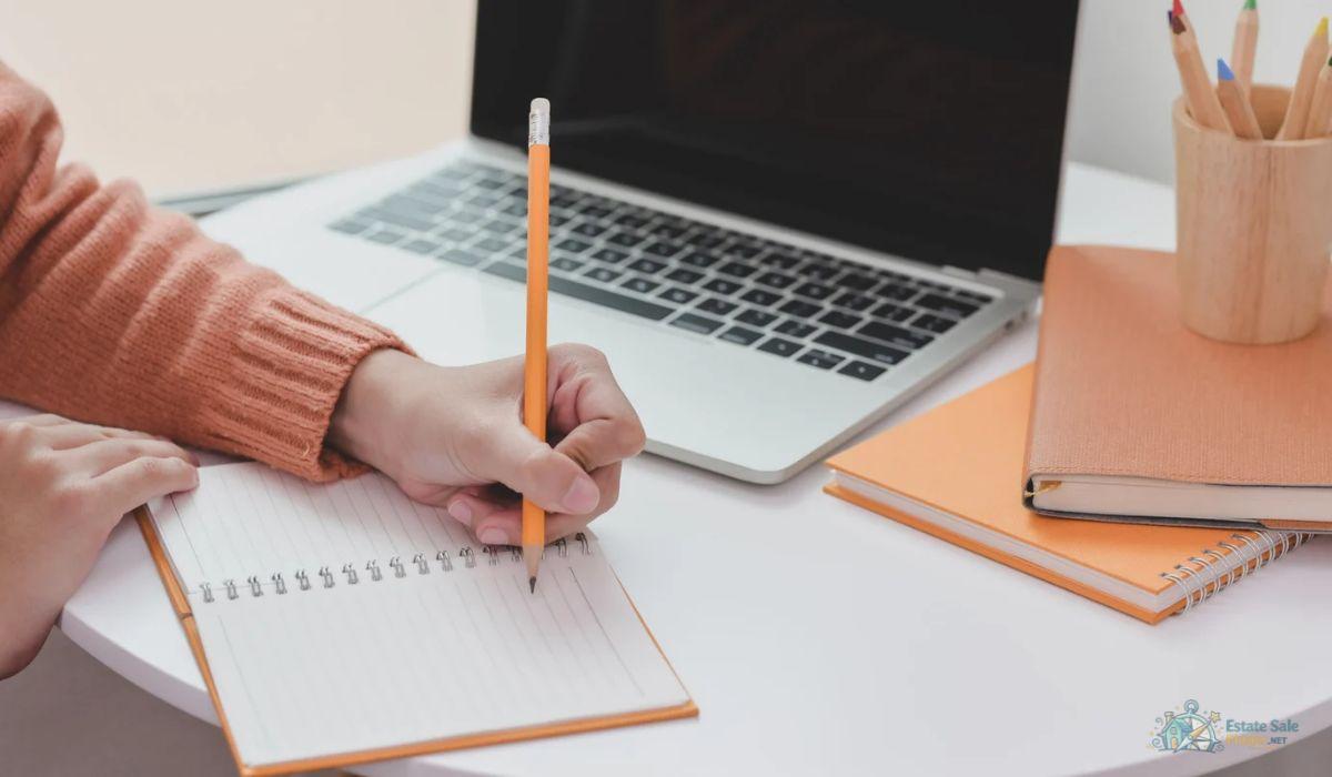 Planning an estate sale advertisement with a written checklist beside a laptop
