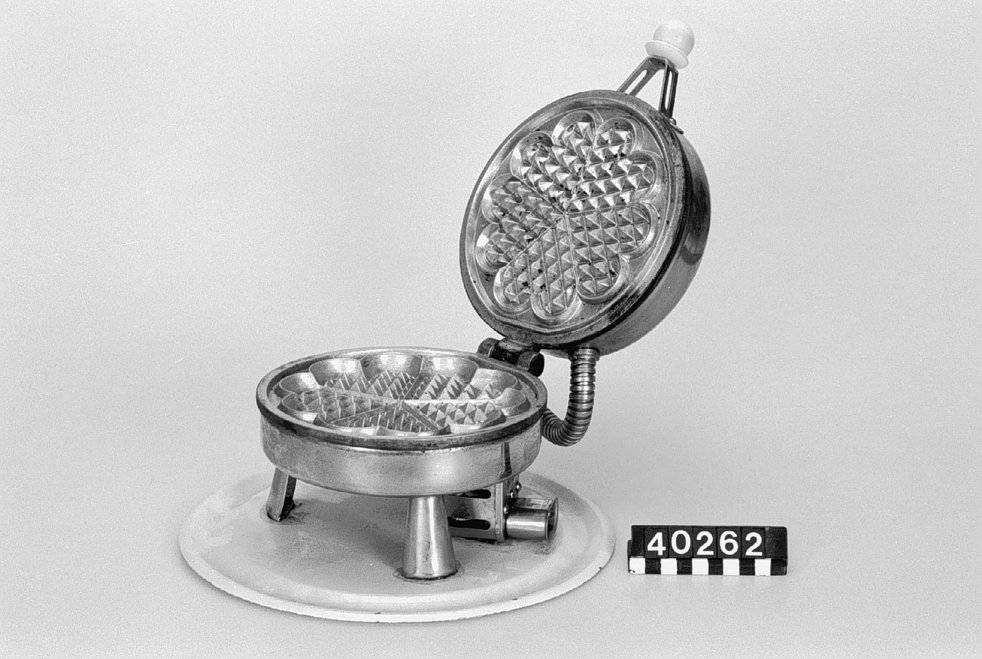 A real 1920 Eleiko electric waffle iron with a round metal body and long handle