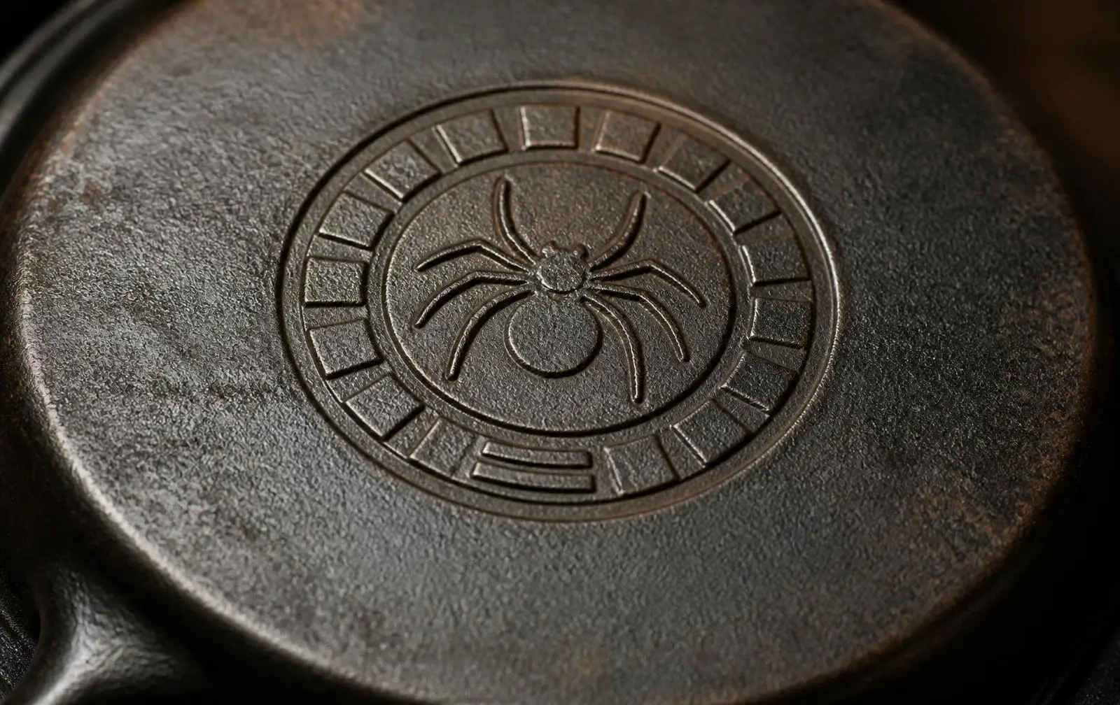 Detail of a vintage cast iron skillet's underside showing the Griswold-style spider logo