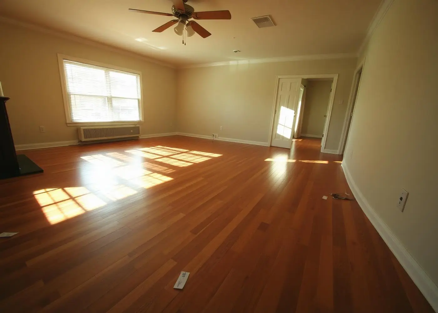 Sunlit empty living room with hardwood floors and a few price tags