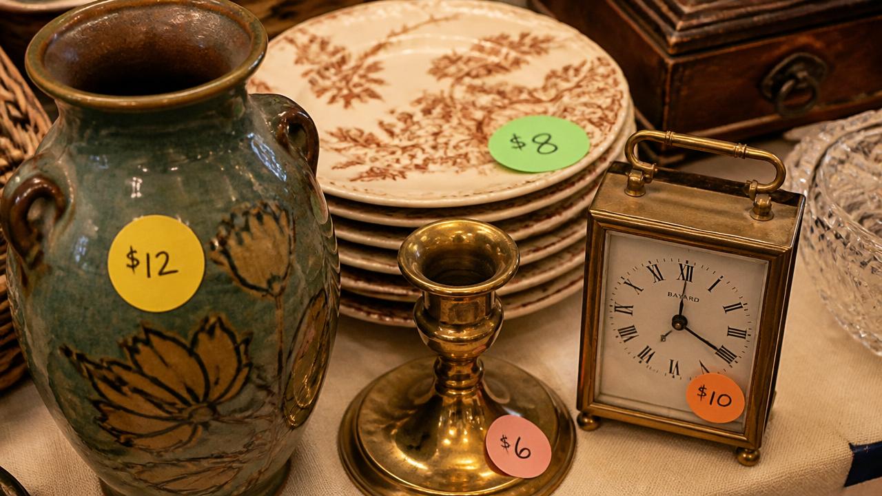 Vintage household items on a table each marked with a plain colored price sticker showing a handwritten dollar amount