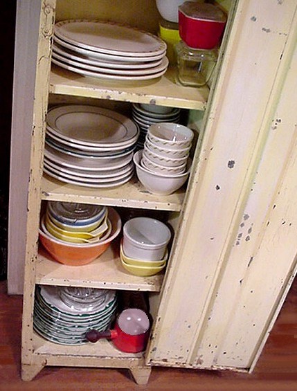 A cabinet stacked with colorful vintage Pyrex bowls and dishes — the kind of haul you stumble onto at estate sales every weekend.