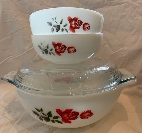 Two vintage Pyrex nesting bowls with a delicate red rose pattern on white opal glass — a classic example of a desirable patterned set.